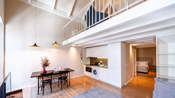 Een modern appartement met een eethoek, keuken, wasruimte en een slaapkamer op een entresol.