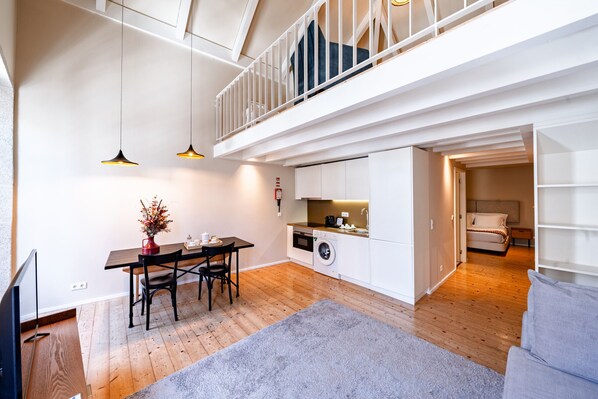 A modern apartment with a dining area, kitchen, and a balcony.