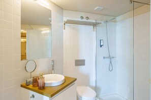 Une salle de bain moderne avec une douche à parois de verre, un lavabo blanc et un miroir.