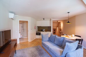 A modern living room with a grey sofa, a wooden coffee table, and a TV on a wooden stand. - Typical One-Bedroom Apart for 3 in Center (Oporto)