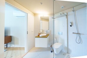 A modern bathroom with a glass shower enclosure, a white sink with a wooden countertop, and a visible toilet. - Typical One-Bedroom Apart for 3 in Center (Oporto)