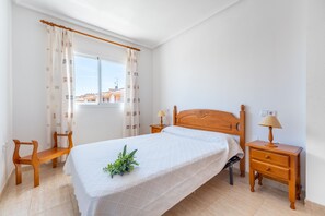 Una camera da letto con un letto, due comodini in legno, una panca e una finestra con tende.