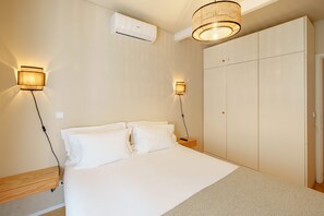 Ein Schlafzimmer mit einem Bett, Nachttischlampen, einer Klimaanlage und einem Kleiderschrank.
