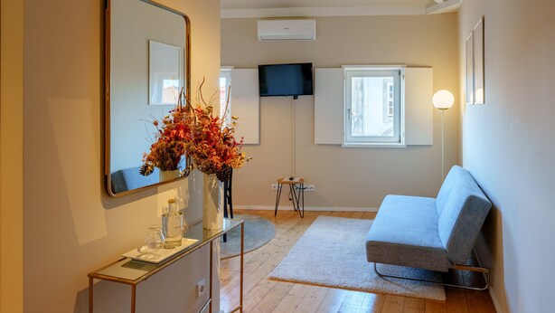A modern room with a sofa, a mirror, a flat-screen TV, and a vase with flowers. - Top Floor One Bedroom Apart for 3 nice Views (Oporto)