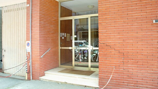 A building entrance with a glass door, a metal gate, and a brick wall. - Apartment "Sunrise" close to the Sea with Wi-Fi (Santa Margherita Ligure)