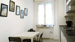 A small kitchen with a white table and chairs, a window with lace curtains, and framed pictures on the wall. - Apartment "Sunrise" close to the Sea with Wi-Fi (Santa Margherita Ligure)
