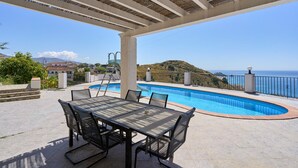 An outdoor pool area with a table and chairs, a pergola, and a view of the sea. - Villa "Casa Beto" with Sea View, Pool, Garden & Wi-Fi (Almuñecar)