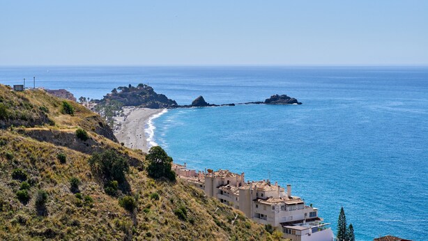 A coastal town with buildings along the beach, rocky outcrops, and clear blue sea. - Villa "Casa Beto" with Sea View, Pool, Garden & Wi-Fi (Almuñecar)