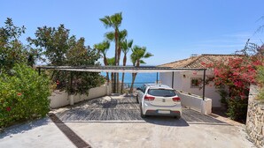 A white car parked in a covered driveway with a view of the sea and palm trees. - Villa "Casa Beto" with Sea View, Pool, Garden & Wi-Fi (Almuñecar)
