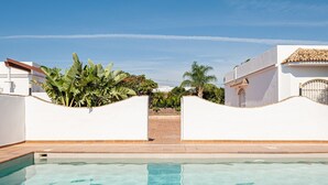 Une piscine à l’eau d’un bleu cristallin, entourée de murs blancs et dotée d’une terrasse carrelée.