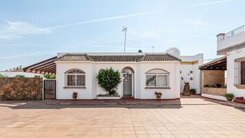 Uma casa de dois andares com telhado ladrilhado, parede de pedra e entrada com calçada.