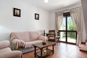 A living room with a sofa, a coffee table, and a dining area with chairs.