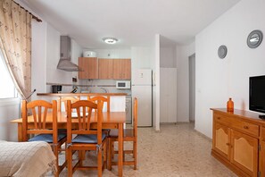 A compact kitchen with wooden cabinets, a microwave, and a refrigerator.