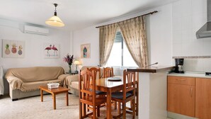A compact living space with a dining table, chairs, a sofa, a coffee machine, and a kitchen area.