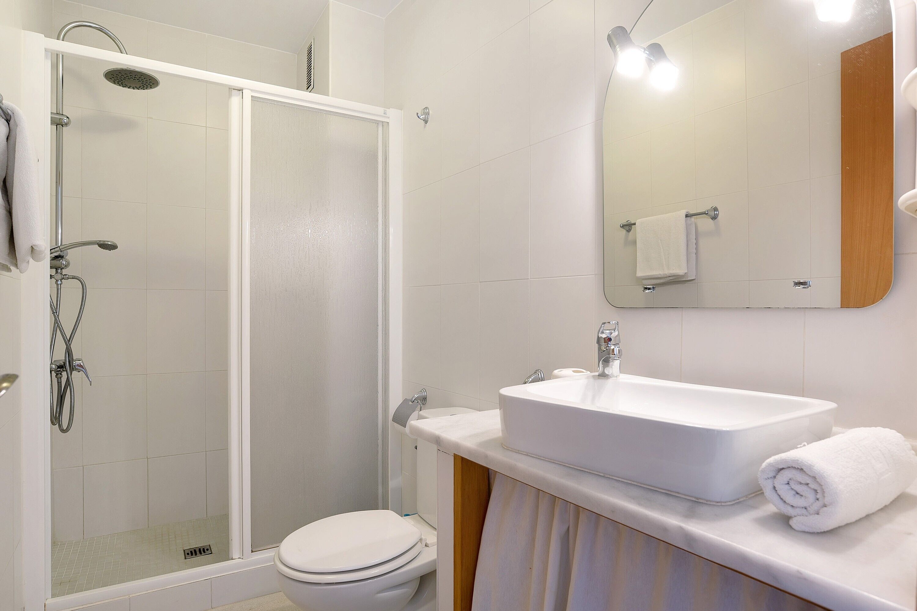 Une salle de bain équipée d’une douche, de toilettes, d’un lavabo et d’un miroir.