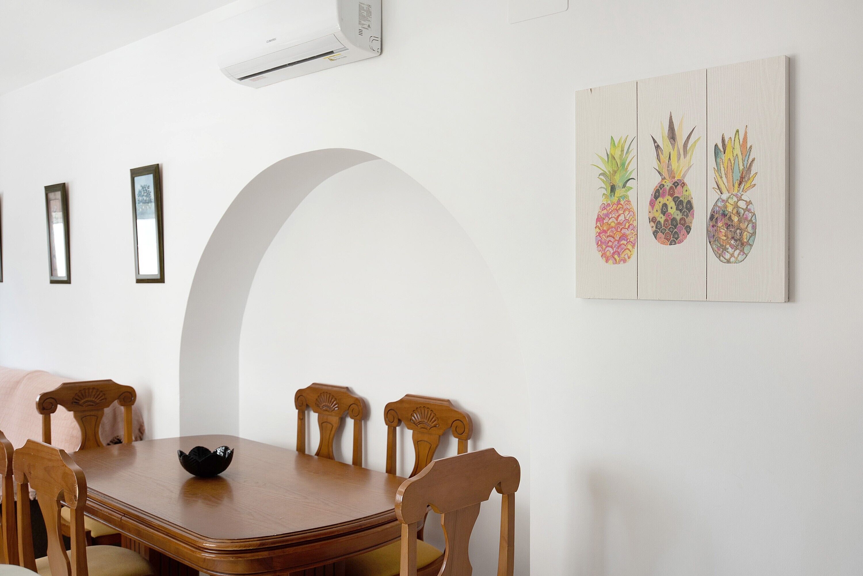 A dining area with a wooden table, chairs, and a wall-mounted air conditioner.