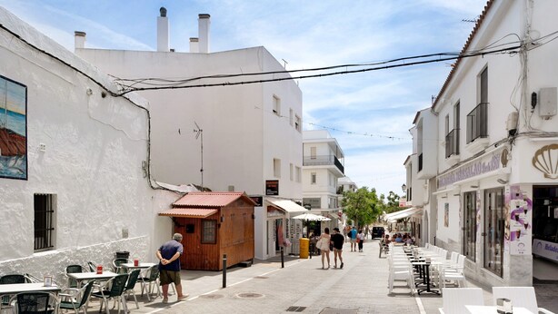 A narrow street with outdoor seating, white buildings, and a wooden structure. - Holiday Home "Almadraba 2 - Andalmar" close to the Sea with Wi-Fi (Conil)