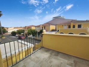 A residential area with yellow buildings, a clear sky, and a parking lot with cars.