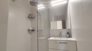 A modern bathroom with a glass shower enclosure, a white sink, and a mirror above the vanity.