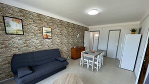 A living room with a stone wall, a dark sofa, a coffee table, and a dining area with a table and chairs.
