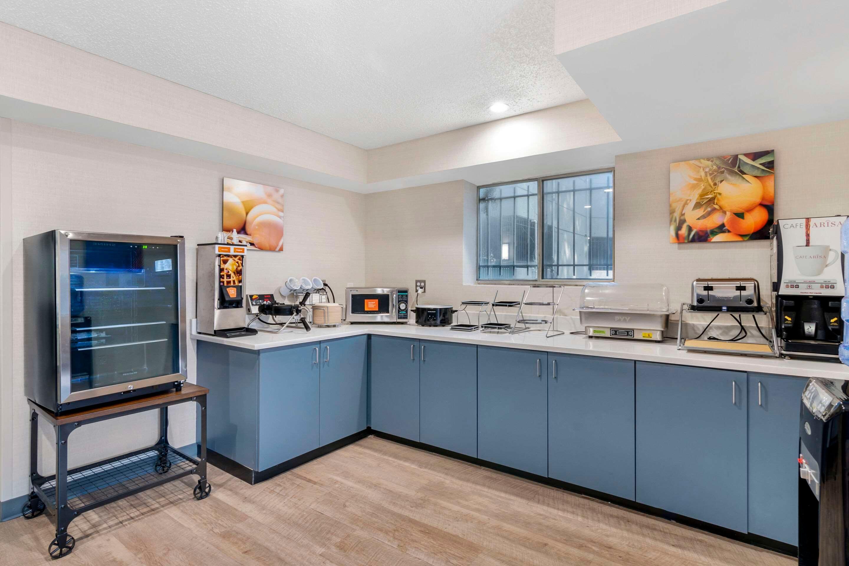 A modern kitchen with blue cabinets, a large oven, a microwave, and a coffee machine.