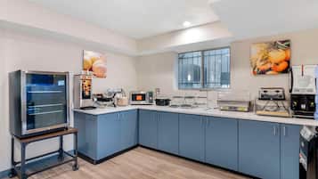A modern kitchen with blue cabinets, a large oven, a microwave, and a coffee machine.