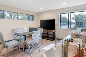 A modern room with a dining area, a flat-screen TV, and a view of the outside.