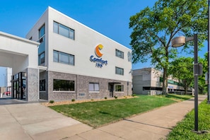 A modern building with a Comfort Inn sign, large windows, and a well-maintained lawn.