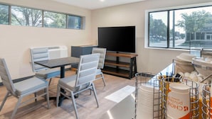 A modern room with a dining area, a flat-screen TV, and a view of the outside. - Comfort Inn (Kansas City)
