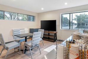 A modern room with a dining area, a flat-screen TV, and a view of the outside.