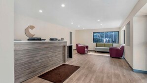 A modern reception area with a wooden reception desk, a large window, and two seating areas with chairs. - Comfort Inn (Kansas City)