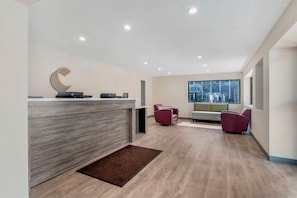 A modern reception area with a wooden reception desk, a large window, and two seating areas with chairs.