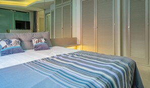 A hotel room with a bed, a television, and a wardrobe. - Duplex in Old Town Palamós: 300m from Beach, Terrace & Chill-out Zone (Palamós)