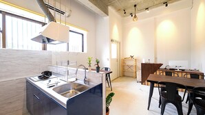 Eine moderne Küche mit Kochinsel, integrierten Geräten und einem Essbereich mit Holztisch und Stühlen.