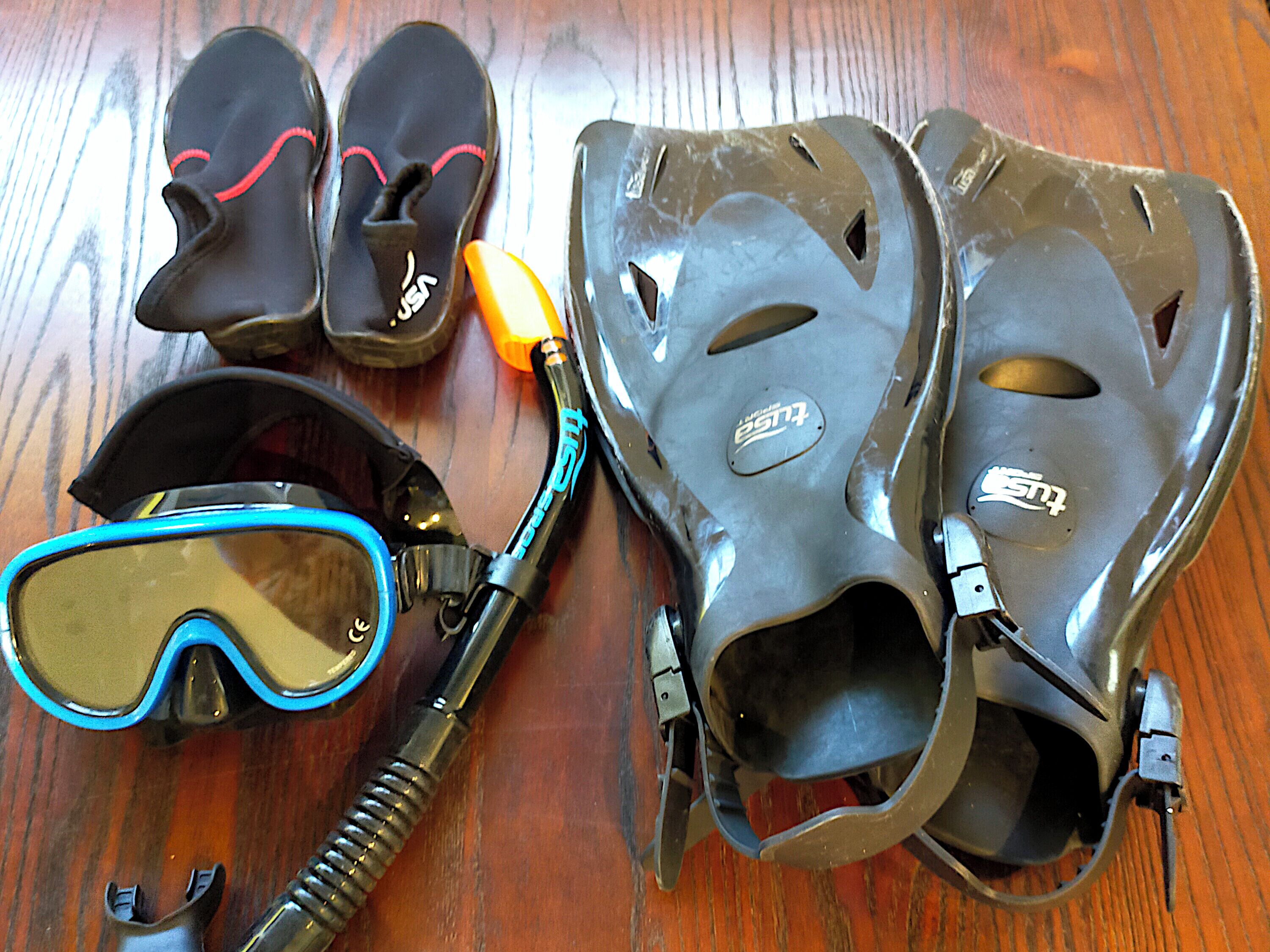 Un par de zapatos negros con cordones rojos, una máscara de buceo con adornos azules y un casco de buceo con boquilla.