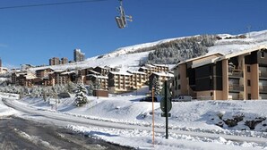 Et snedækket skisportssted med flere bygninger, heriblandt et stort hotel med altaner og en fungerende gondollift.