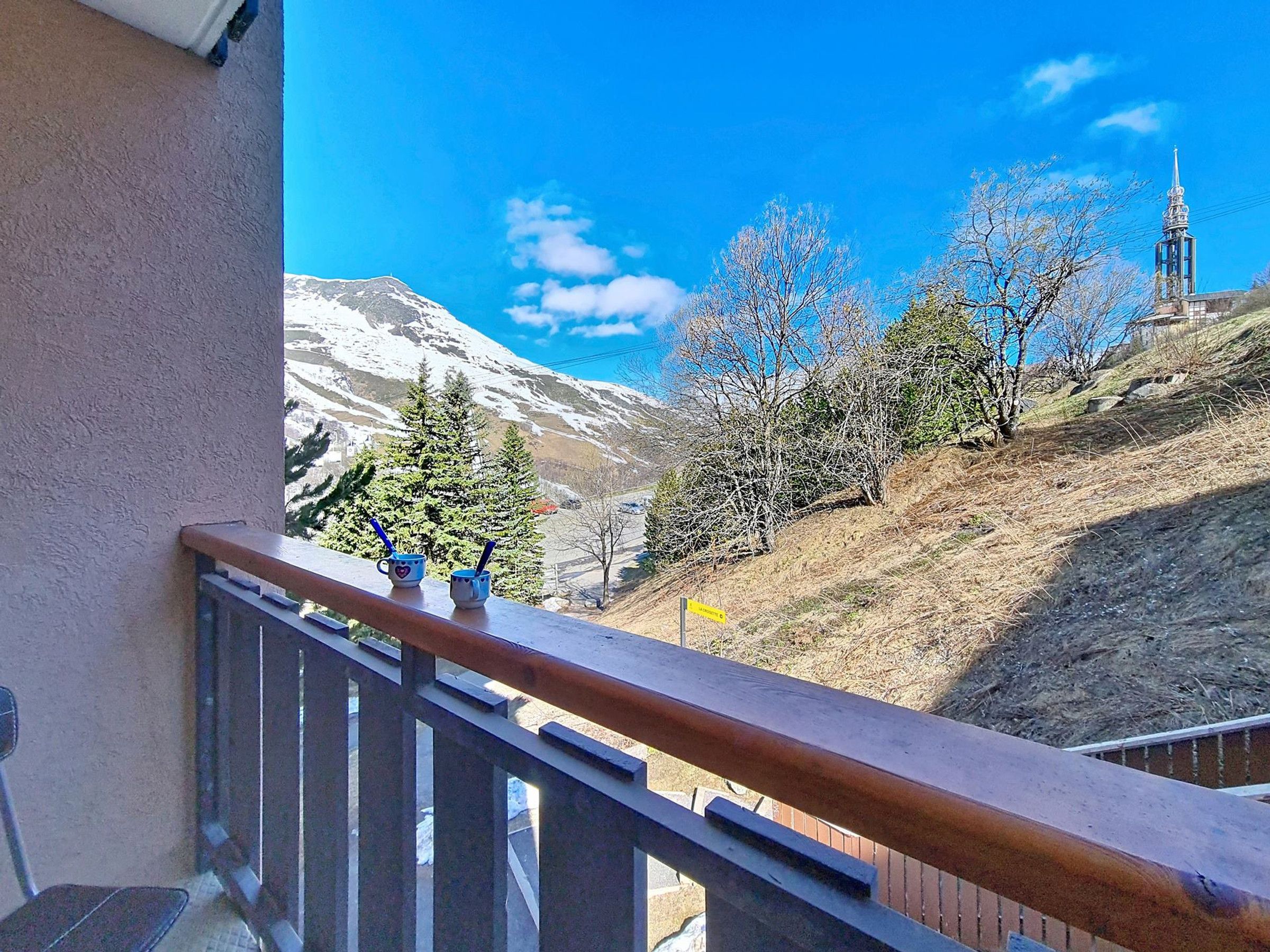 Un balcon avec vue sur une montagne et le clocher d’une église.