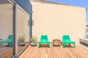 A wooden deck with two green chairs, a small table with drinks, and potted plants. - Premier Artful City Loft with Terrace (Chania)