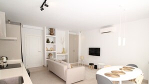 A modern living space with a kitchen, dining area, and a sofa. - Modern Duplex Apartment Near Beach & Center - Del Parque Flats Constancia V3 (Málaga)