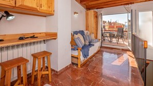 A cozy room with a bed, wooden stools, a radiator, and a view of the outside. - Charming Village House with Terrace, Near Beach, WiFi, Garage & Fully Equipped Kitchen (Palamós)