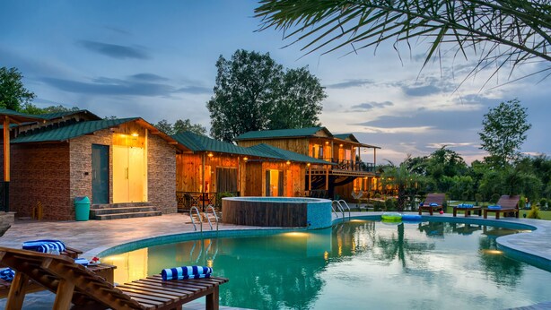 A poolside area with wooden lounge chairs, a hot tub, and a pool. - Pumpkin Hotels Corbett, Tusk N Wood (Ramnagar)