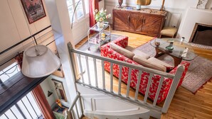A staircase leading to a living room with a red sofa, a wooden cabinet, and a painting on the wall. - Style Bohème, by Veeve (Paris)