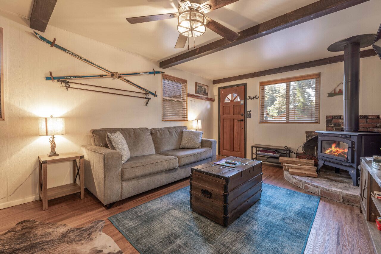 A cozy living room with a sofa, a wooden coffee table, a fireplace, and skis mounted on the wall.