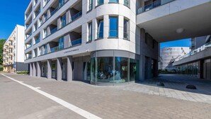 A modern building with a curved facade, multiple balconies, and large windows.