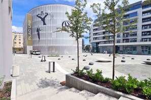 A modern building with a curved facade and a sign reading "PLAC UNI". - Comfortable Apartment in Downtown Gdynia | Near the Beach | Parking (Gdynia)