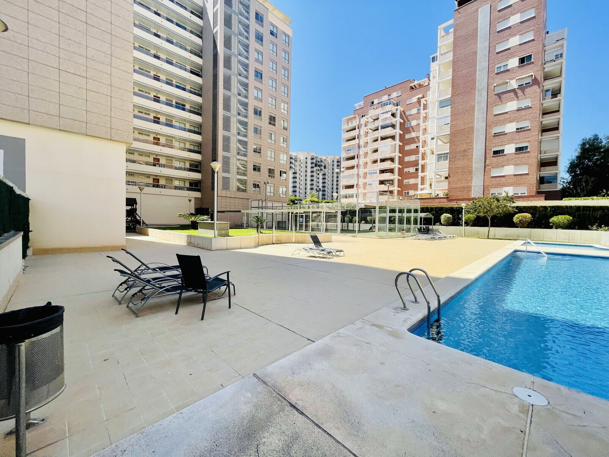 A pool area with lounge chairs and a clear view of surrounding high-rise buildings.