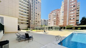 A pool area with lounge chairs and a clear view of surrounding high-rise buildings. - A839 - A spacious apartment with garage, air conditioning and pool (Villajoyosa)