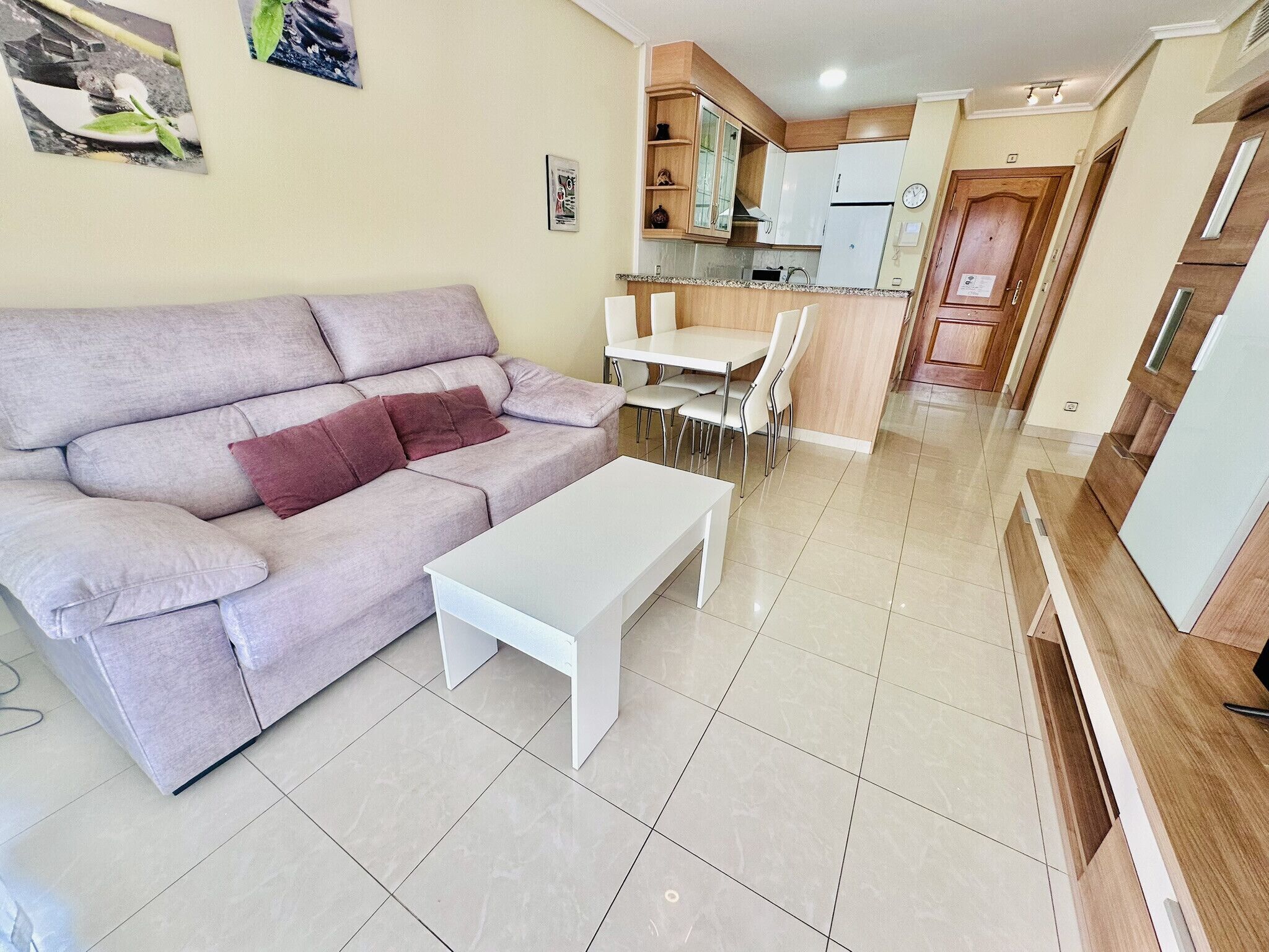 A living room with a sofa, a coffee table, and a dining area with chairs and a table.