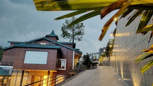 A building with a sloped roof, a visible staircase leading to the entrance, and a paved pathway. - Kaithal Resort - Kasauli (Kasauli)