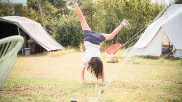 A person performing a handstand in a grassy area with tents in the background.